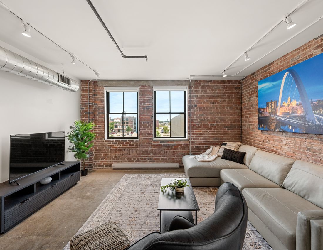 Harbach Lofts two-bedroom living room with an industrial accent wall and original brick
